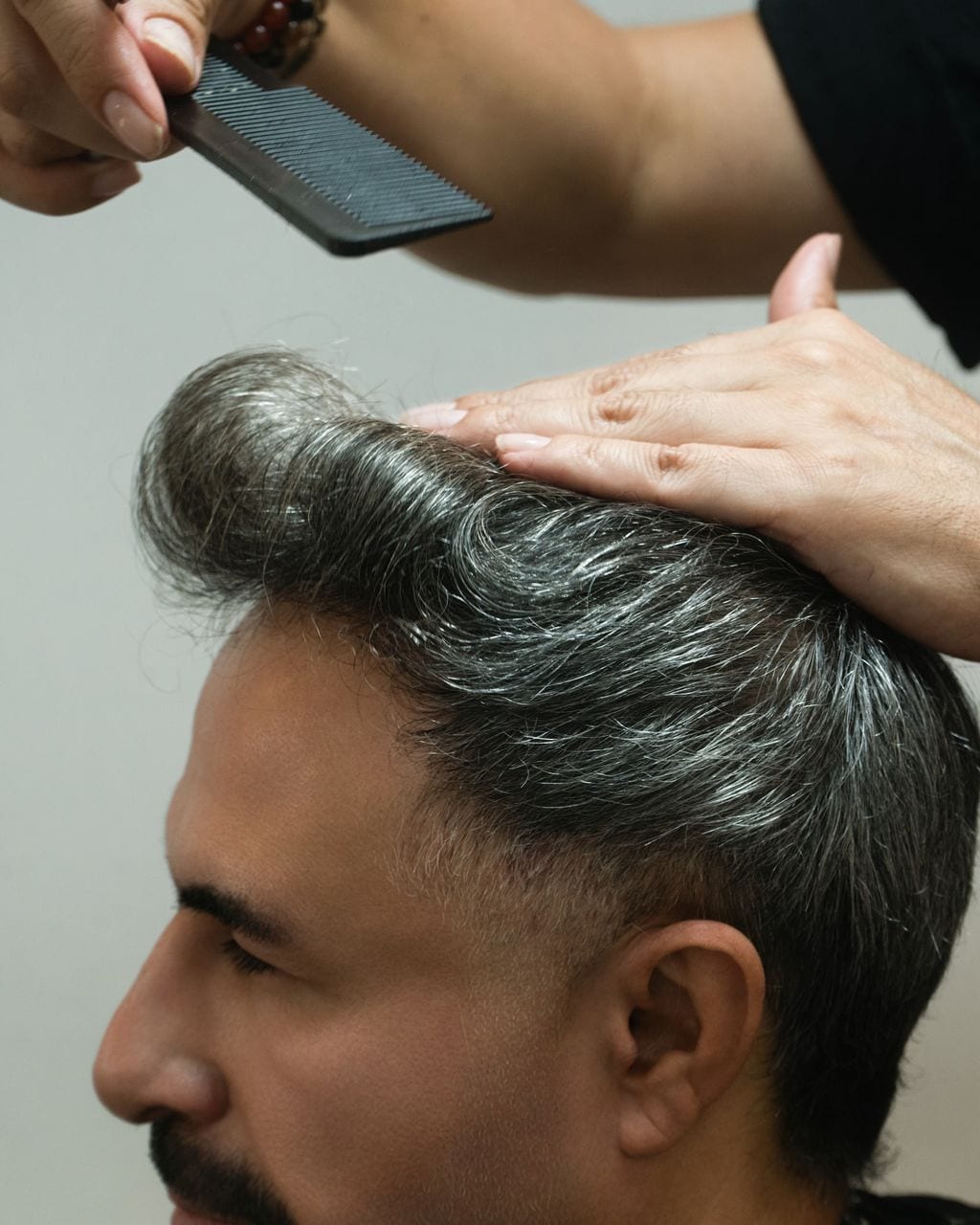 Silver hair lifted with a comb and hand to check texture