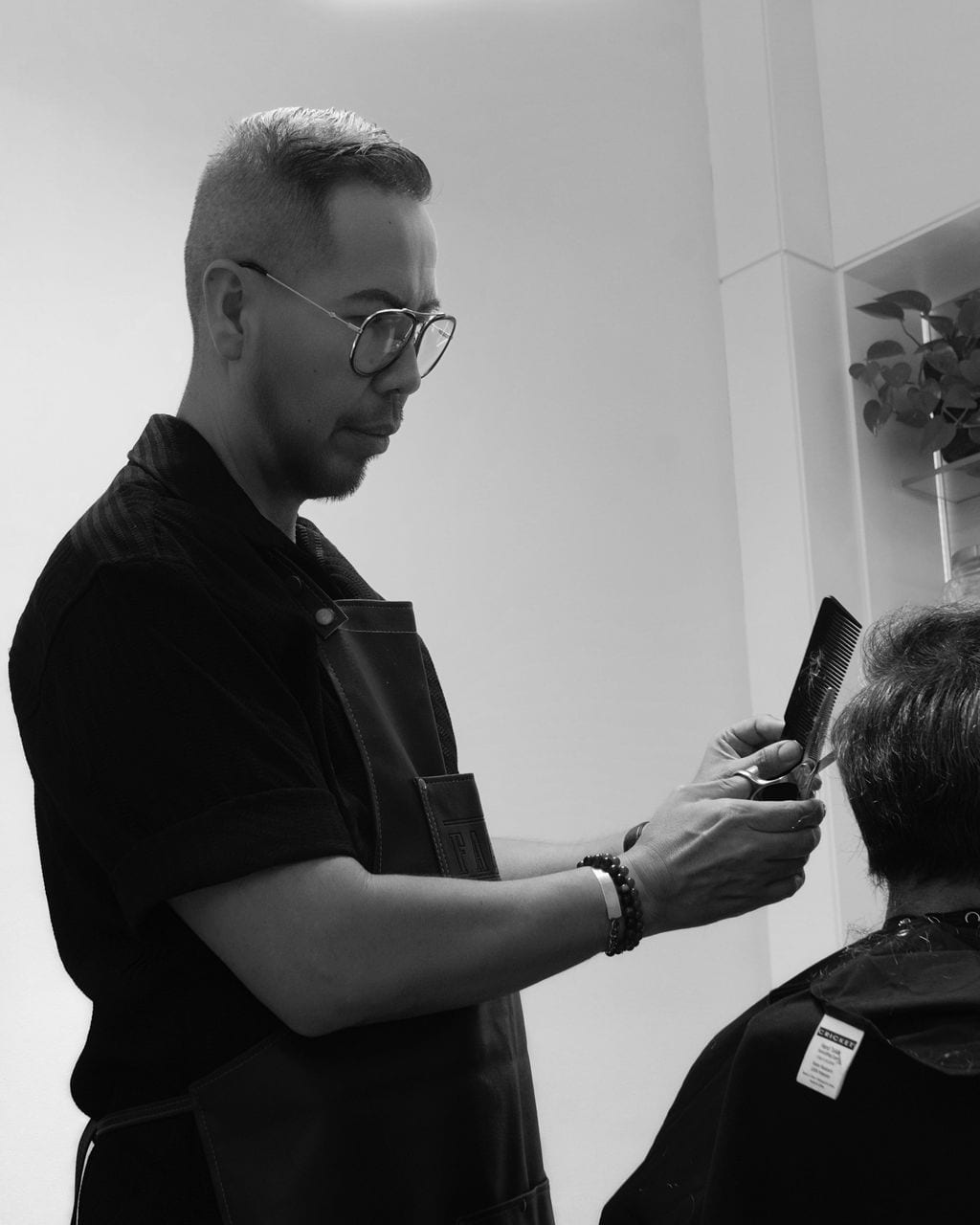 Moses in profile, working with comb and scissors, in black and white