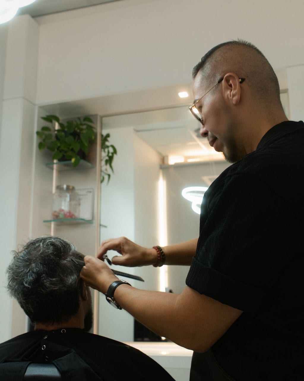 Moses cutting a client's hair beside the studio mirror
